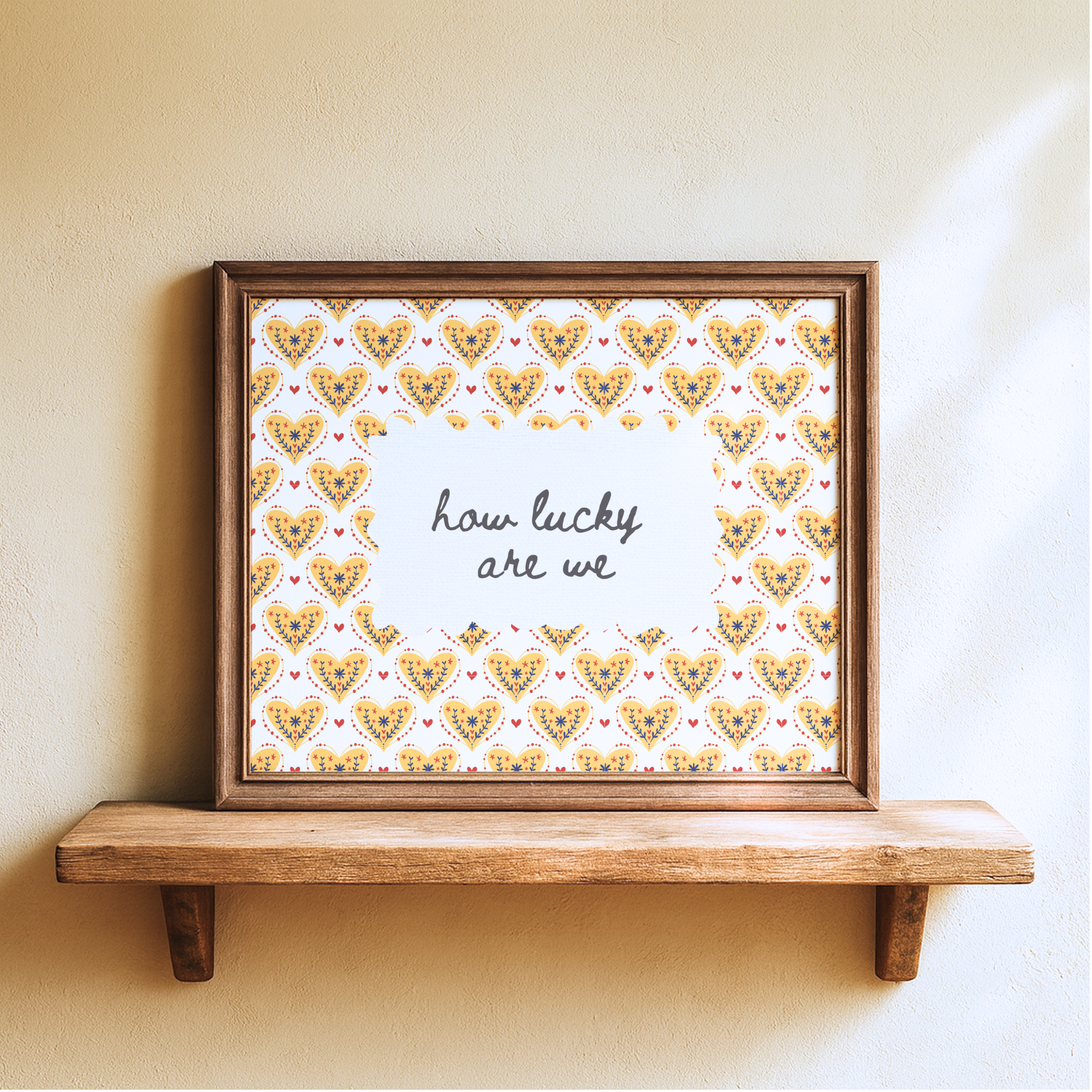 Framed artwork with heart pattern and 'how lucky are we' text on a wooden shelf.