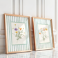 Two framed botanical prints with floral illustrations on a white paneled wall.