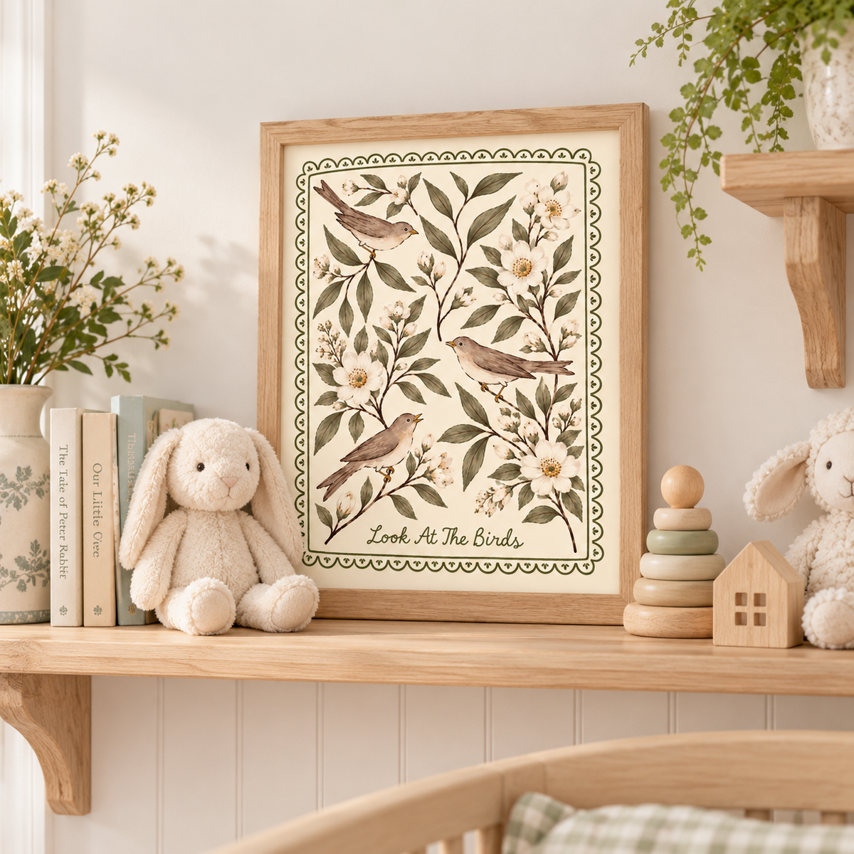 Christian nursery wall art featuring three songbirds and white flowers in a natural wood frame displayed on a nursery shelf with plush bunnies, children's books, and wooden toys.