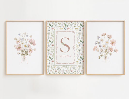 Flower nursery wall art set of 3 featuring blush pink and sage florals. This set completes the look of a cottagecore nursery decor with 2 flower bouquets and a center print with delicate pink flowers and a name sign with a bow across the name initial. Girl nursery wall decor.