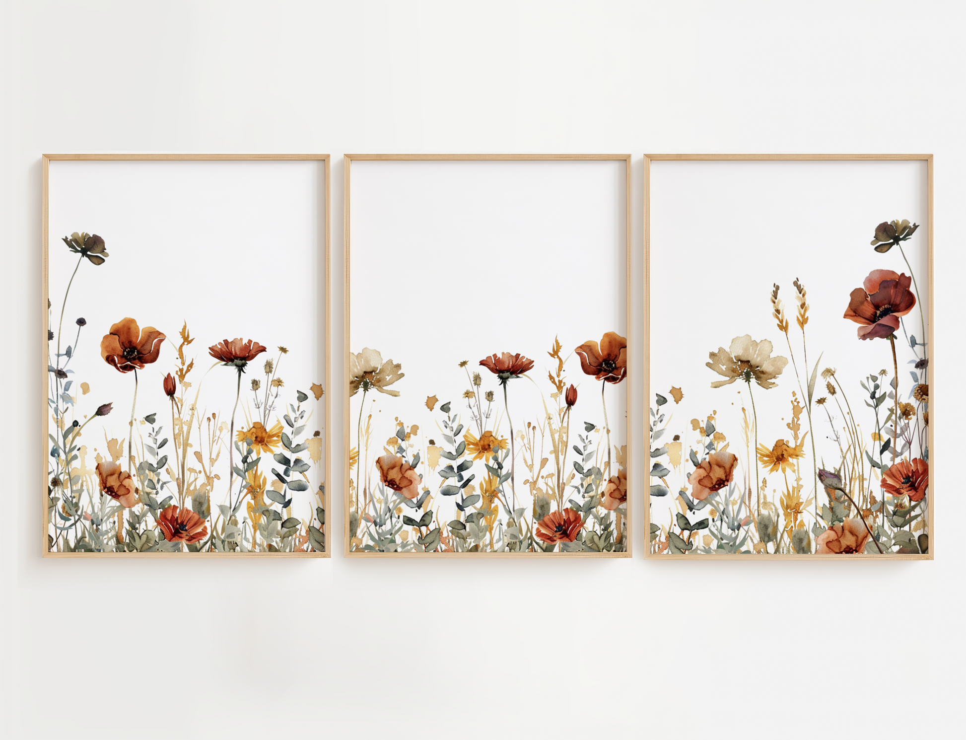 Three framed vertical floral art prints with a watercolor-style wildflower design in muted orange, cream, yellow, and olive tones, displayed side by side on a white wall.