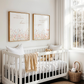 Nursery room with a white crib, teddy bear, and framed artwork on a light-colored wall.