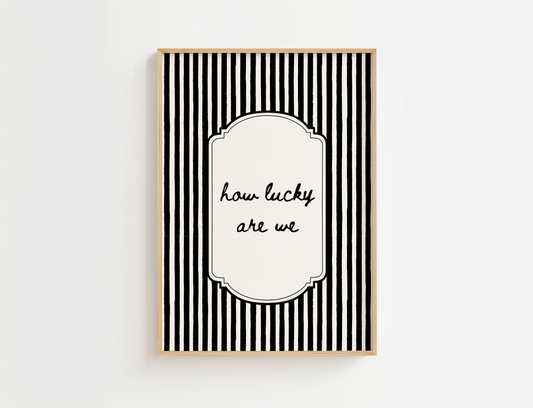 Framed black and white striped print with 'how lucky are we' text on a white background