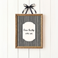 Framed black and white striped print with 'how lucky are we' text on a white wooden background.