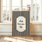 Framed black and white striped art print with text in a room with large windows.
