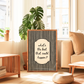 Framed quote 'what's the best that could happen?' in a living room setting with plants and furniture.