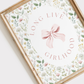 Framed artwork with floral design and 'LIVE LOVE GIRLHOOD' text on a white background