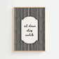 Framed black and white striped wall art with 'sit down stay awhile' text on a white background
