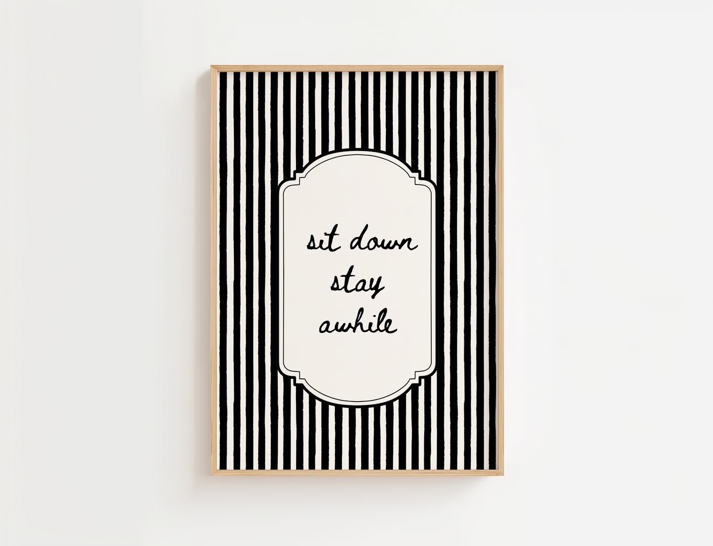 Framed black and white striped wall art with 'sit down stay awhile' text on a white background