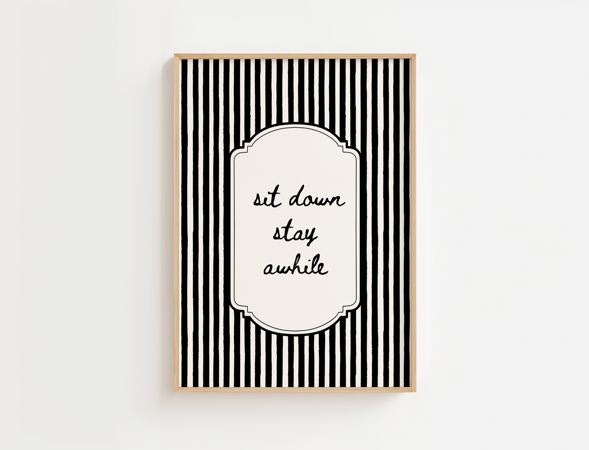 Framed black and white striped wall art with 'sit down stay awhile' text on a white background