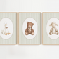 Three framed nursery art prints hanging side-by-side on a white wall. Each print features a soft, textured illustration of a baby animal (a duck, a teddy bear, and a lamb) inside an oval, set against a background of thin vertical stripes in beige and white, all enclosed in light wood frames.