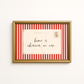 Framed postcard with red and white striped border and 'home is wherever we are' text.