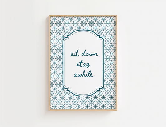 Decorative wall art with patterned border and text 'sit down stay awhile' on a white background